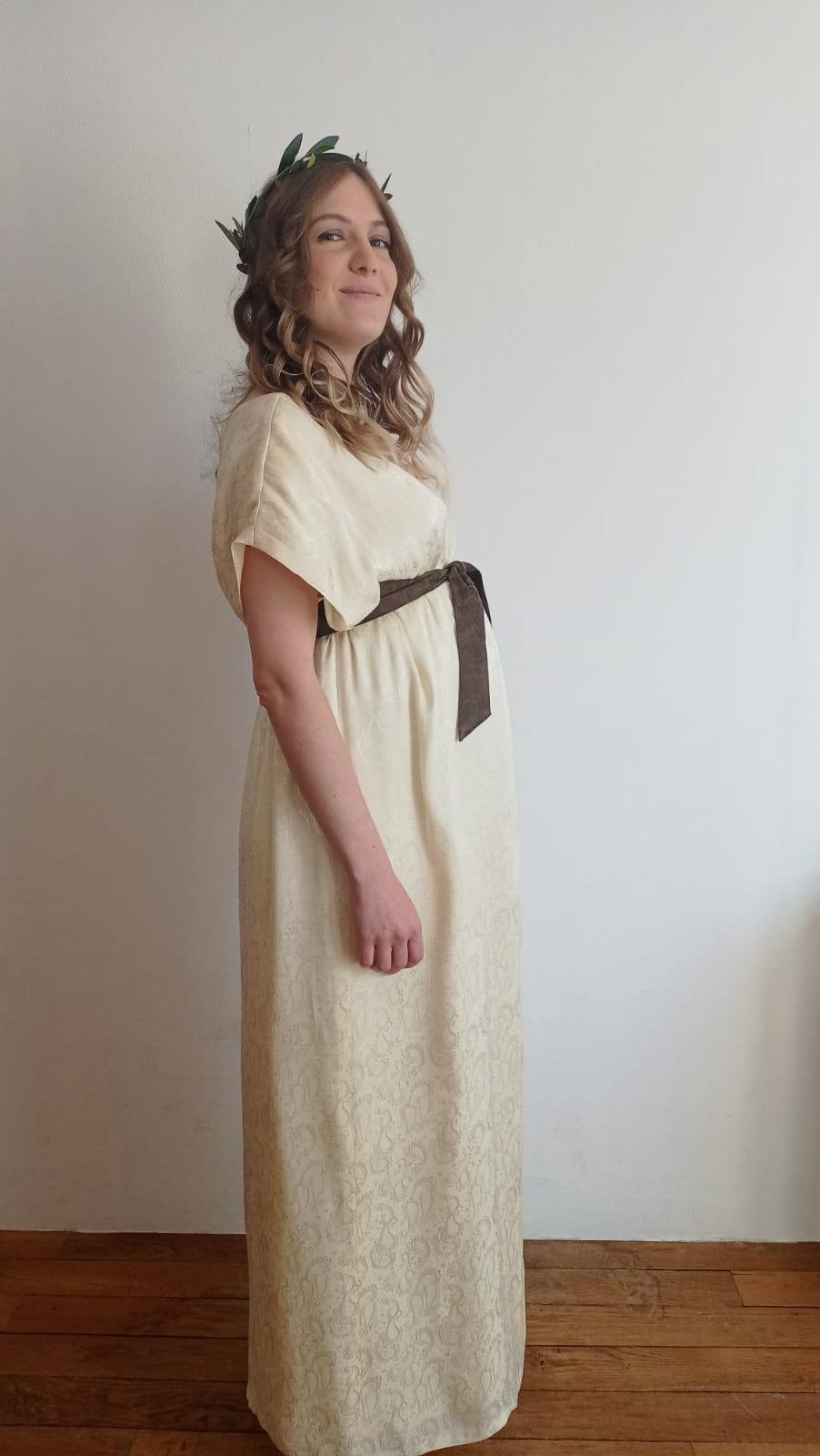 Irina dans sa robe de mariée en satin ivoire à ceinture brune nouée, de profil